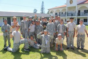 Army and Navy Academy cadets in camouflage uniforms pose as a group on the campus lawn.