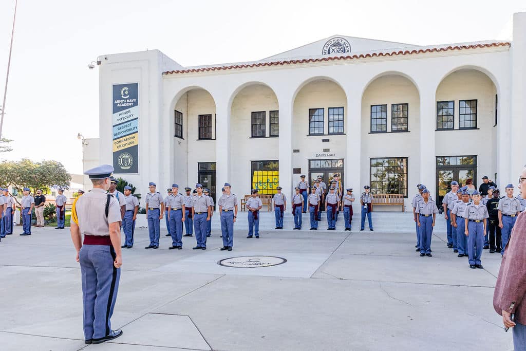 A group of disciplined cadets in uniform stand in formation