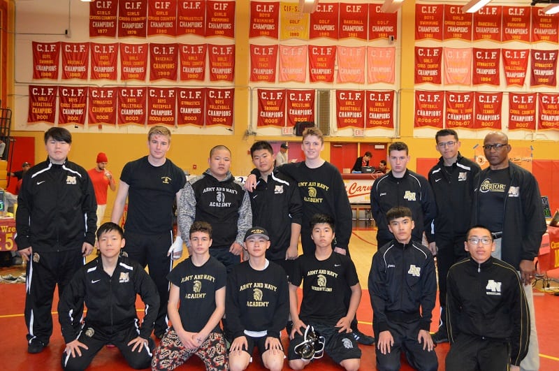 The Academy wrestling team and coaches pose in a gym beneath rows of red CIF championship banners.
