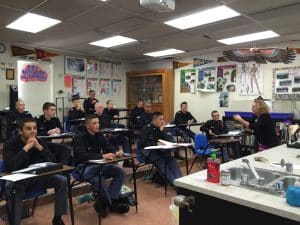An instructor leads a science lesson for Army and Navy Academy cadets in a classroom decorated with posters.