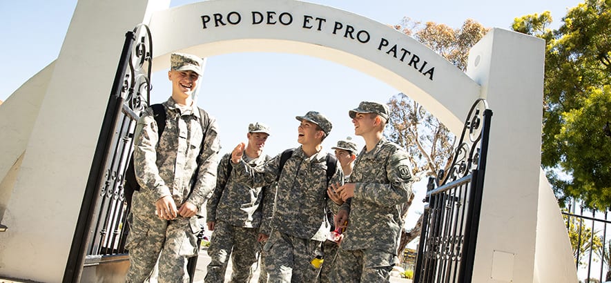 Army and Navy Academy cadets smile beneath the campus arch inscribed with the motto Pro Deo Et Pro Patria.