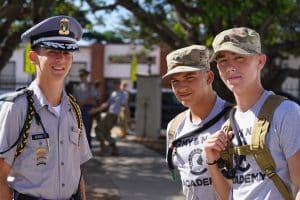 Three cadets smile together on move-in day at Army and Navy Academy, two in camouflage and one in dress uniform.