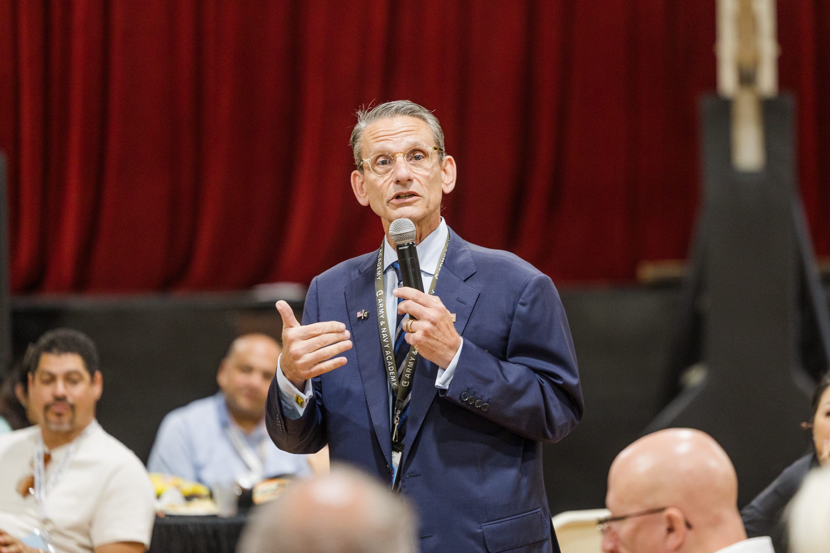Army and Navy Academy President Barry Shreiar addresses an audience with a microphone at a school event.