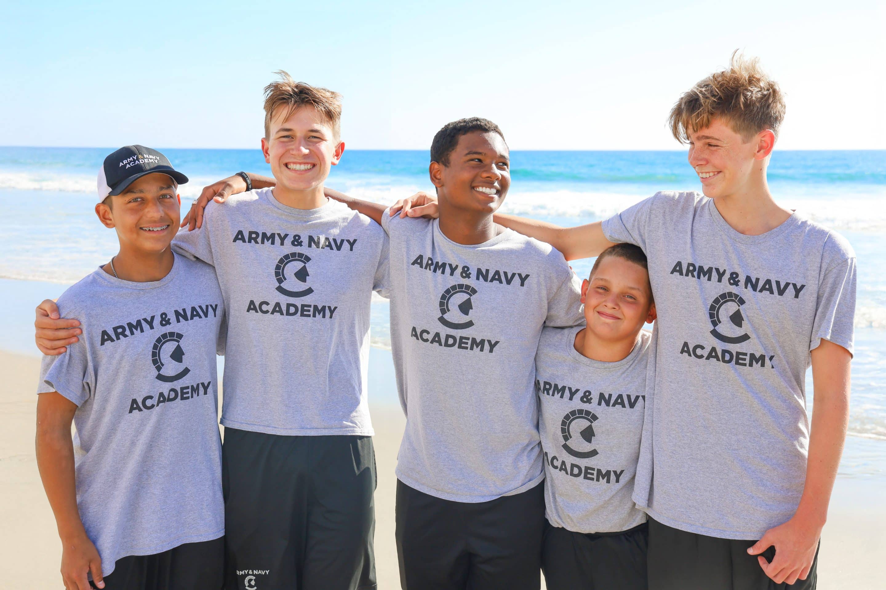 Five Army and Navy Academy cadets smile together on the beach in Carlsbad on a sunny day.