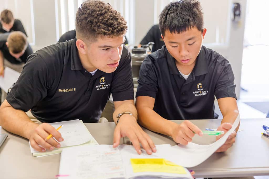 Two Army and Navy Academy cadets work together at a classroom table.