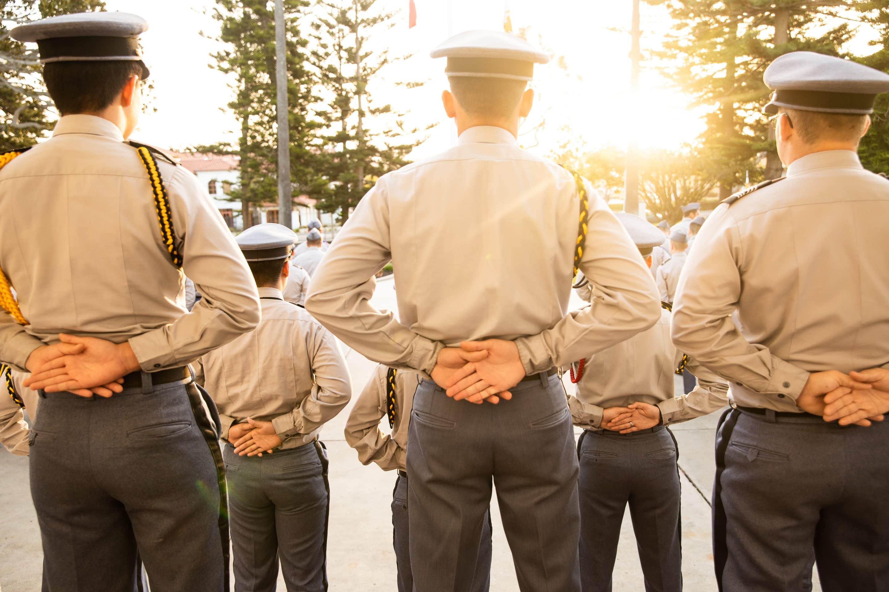 Army and Navy Academy cadets stand at parade rest in dress uniform during a golden-hour morning formation.