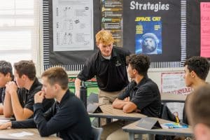 Army and Navy Academy cadet presenting to classmates in a classroom decorated with academic strategy posters.