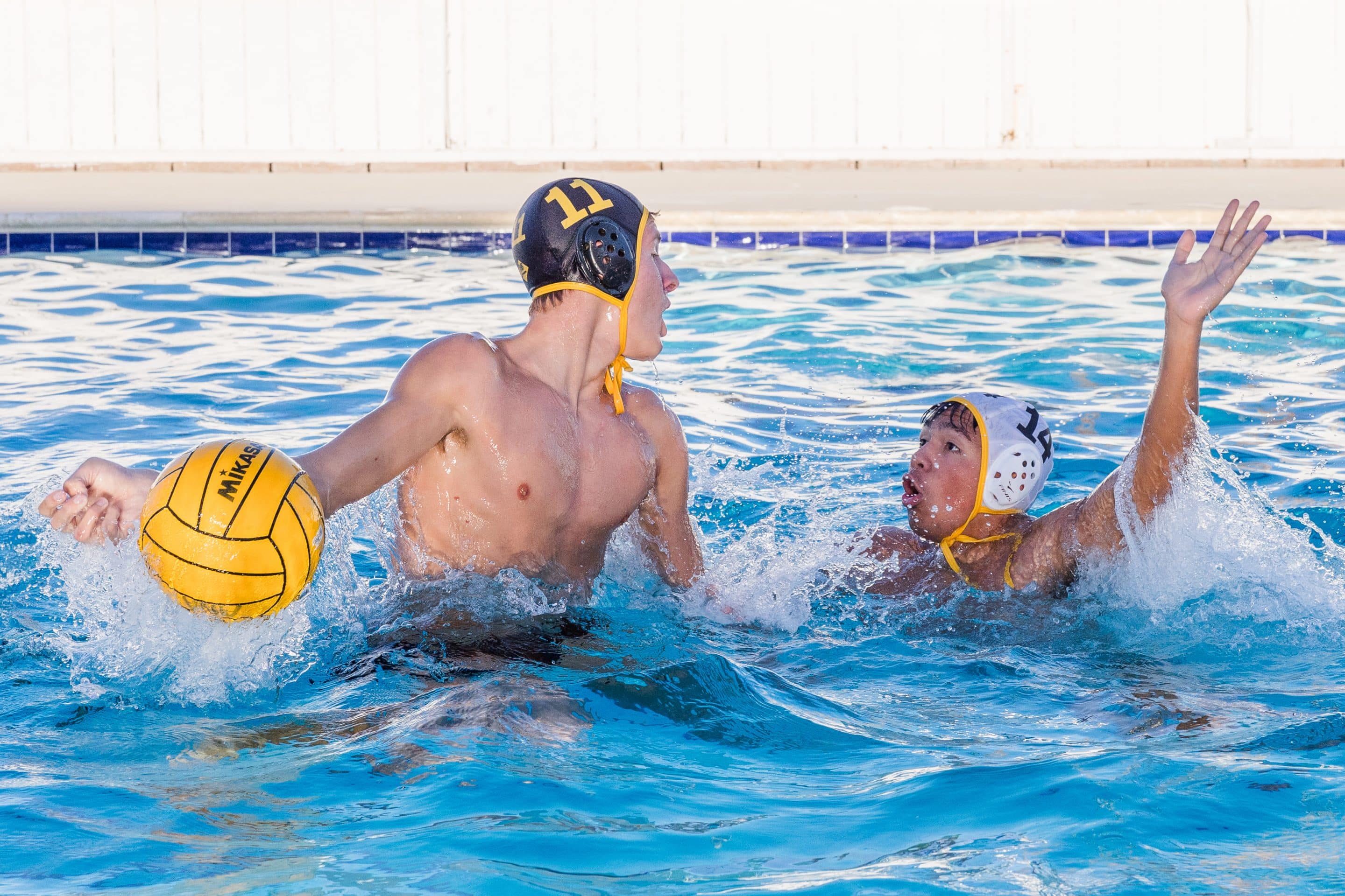 Army and Navy Academy cadet holds the ball while an opposing player defends during a water polo match.