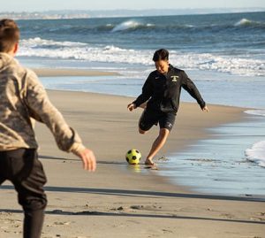 Two Army and Navy Academy cadets play soccer on the beach near the Carlsbad campus.